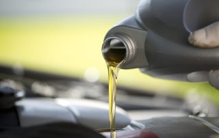A fresh quart of oil is poured into a car engine, elegantly.