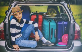 A hip girl in a car trunk looks happy.