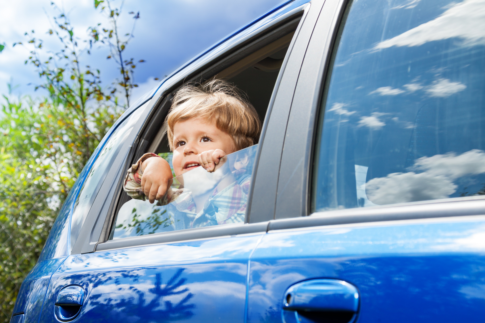 A little boy looks out the window of a car