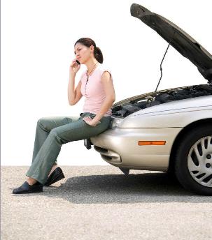 Woman sitting on bumper of broken down car