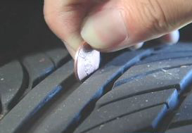 Person testing tire tread with penny