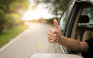 passenger giving a thumbs up as a sign satisfaction from a warrantied vehicle