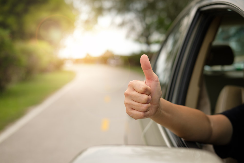 passenger giving a thumbs up as a sign satisfaction from a warrantied vehicle