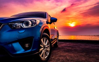 Luxury car parked near beach during sunset