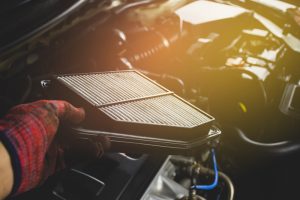 Car air filter in a hand of mechanic man is installing into air