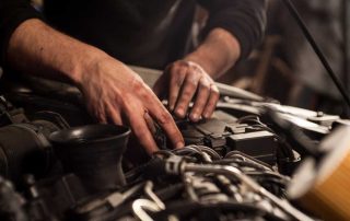 Car mechanic working under the hood of a vehicle