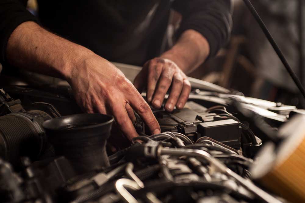 Car mechanic working under the hood of a vehicle