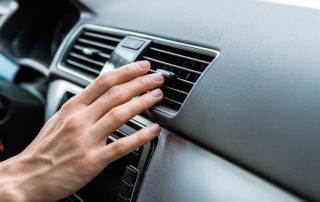 person adjusting air conditioner vent on car dashboard