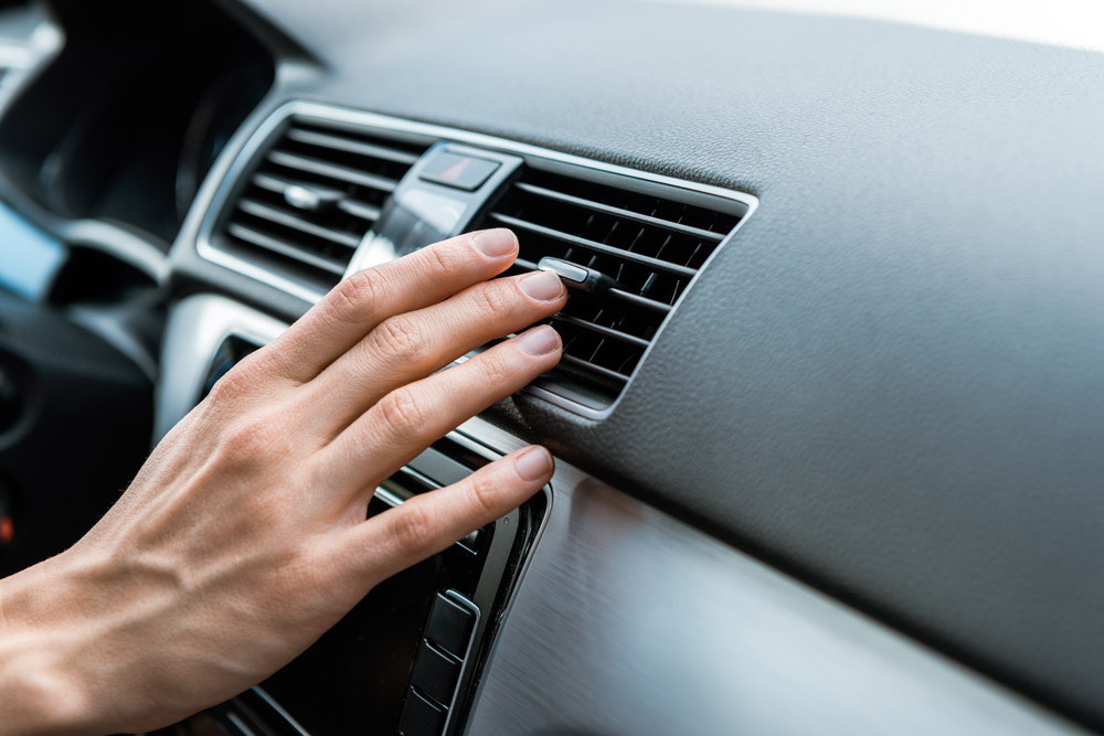 person adjusting air conditioner vent on car dashboard