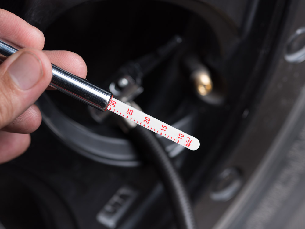 Hand holding tire pressure gauge.