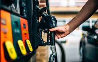 Man at gas pump reaching for the nozzle.