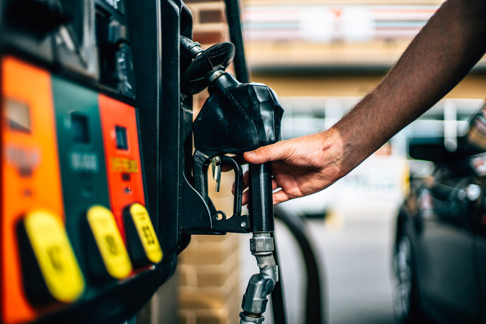 Man at gas pump reaching for the nozzle.