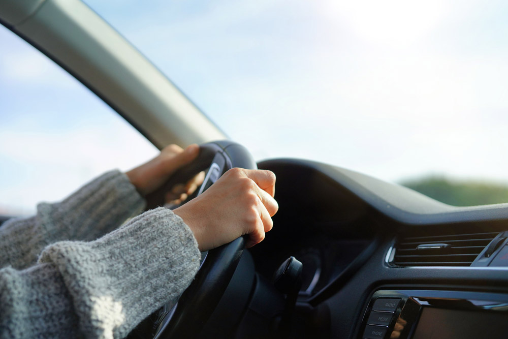 Female gripping car steering wheel.