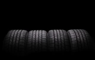 four car tires in front of black background.