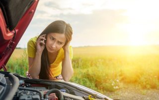 woman checking under hood of car