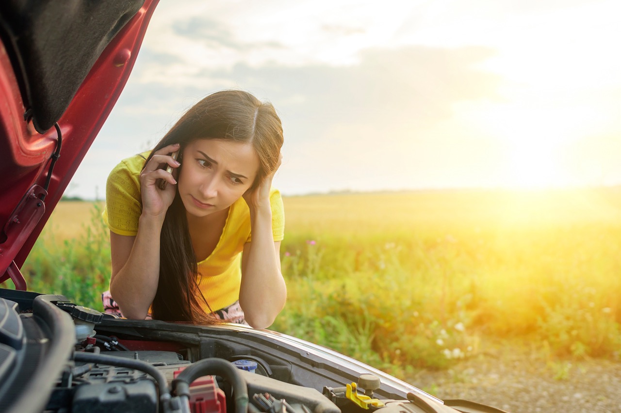 woman checking under hood of car