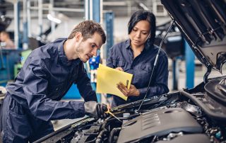 mechanics examine a car engine for repair